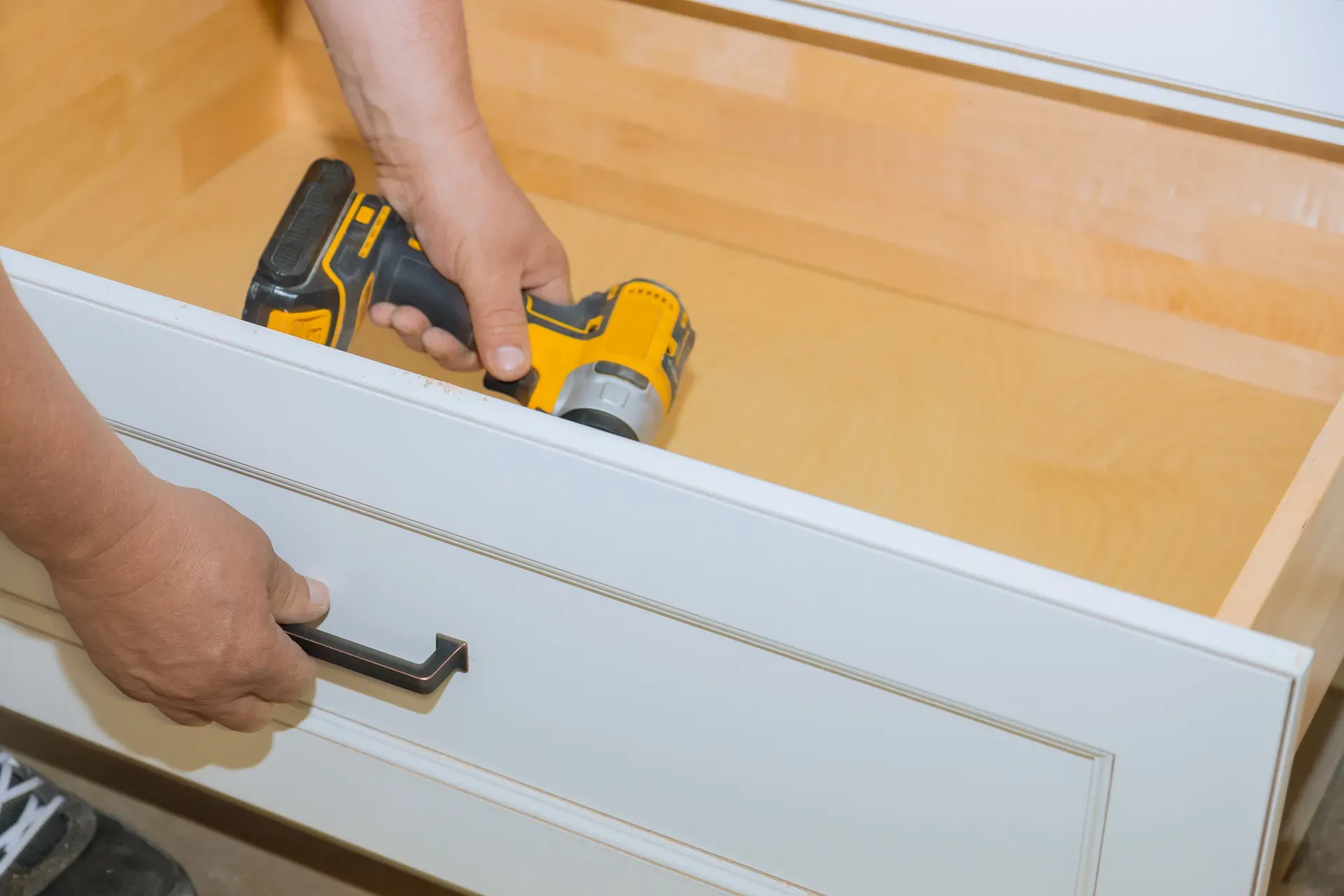A new white drawer front being fitted to the existing maple drawer box beneath it