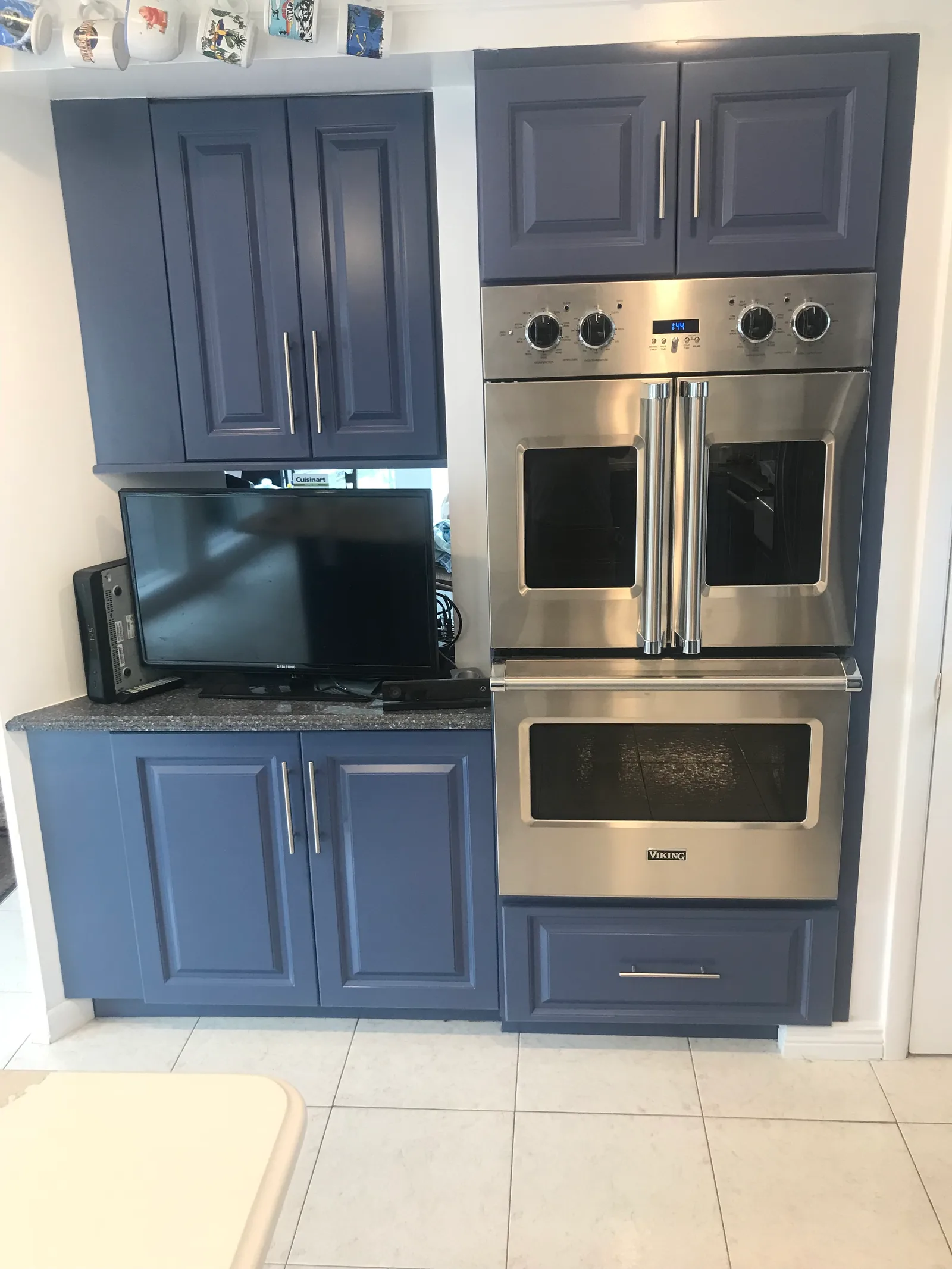 Periwinkle-blue raised-panel cabinets around a stainless double wall oven and built-in microwave